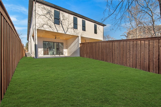 rear view of property featuring a lawn and ceiling fan