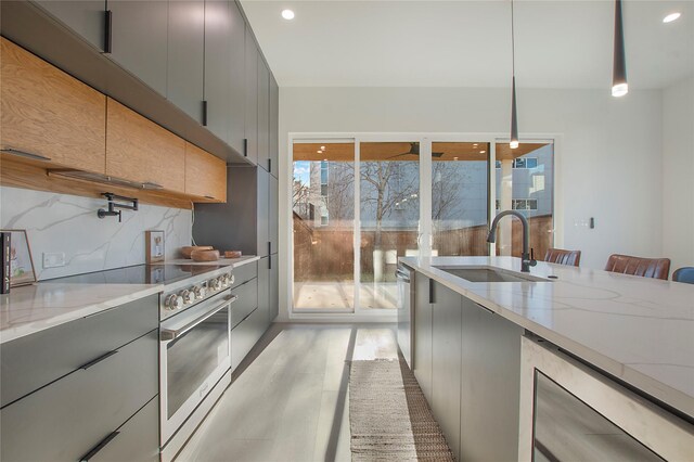 kitchen with sink, stainless steel appliances, backsplash, pendant lighting, and gray cabinets