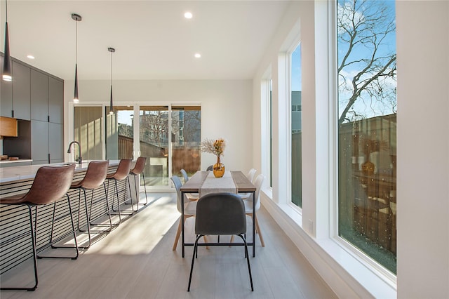 dining area featuring light wood-type flooring, sink, and a wealth of natural light