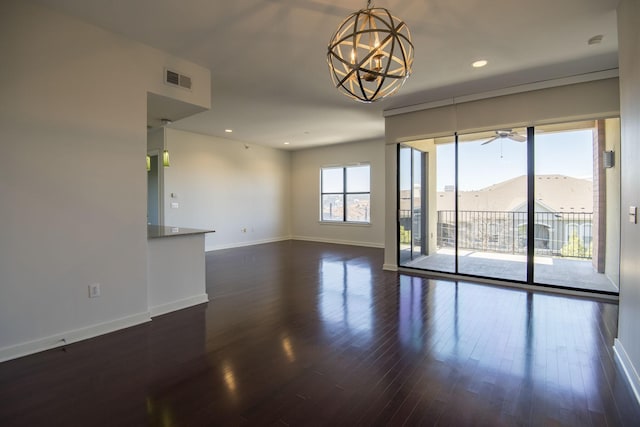 spare room with a mountain view, ceiling fan with notable chandelier, and dark hardwood / wood-style floors