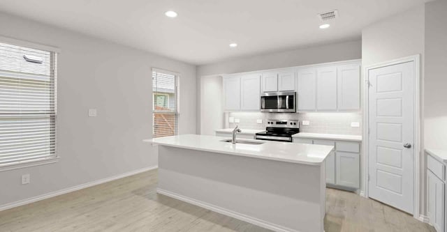 kitchen with appliances with stainless steel finishes, a center island with sink, light hardwood / wood-style flooring, and sink