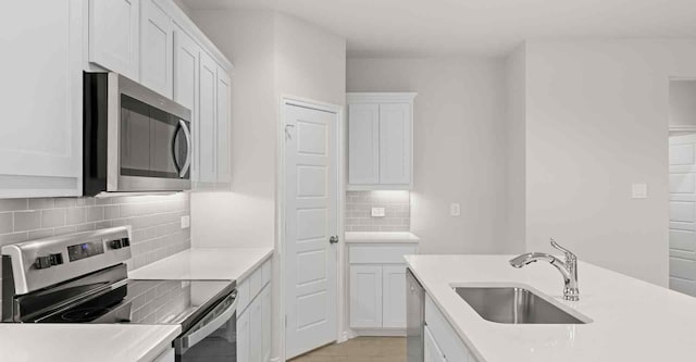 kitchen featuring appliances with stainless steel finishes, tasteful backsplash, white cabinetry, and sink