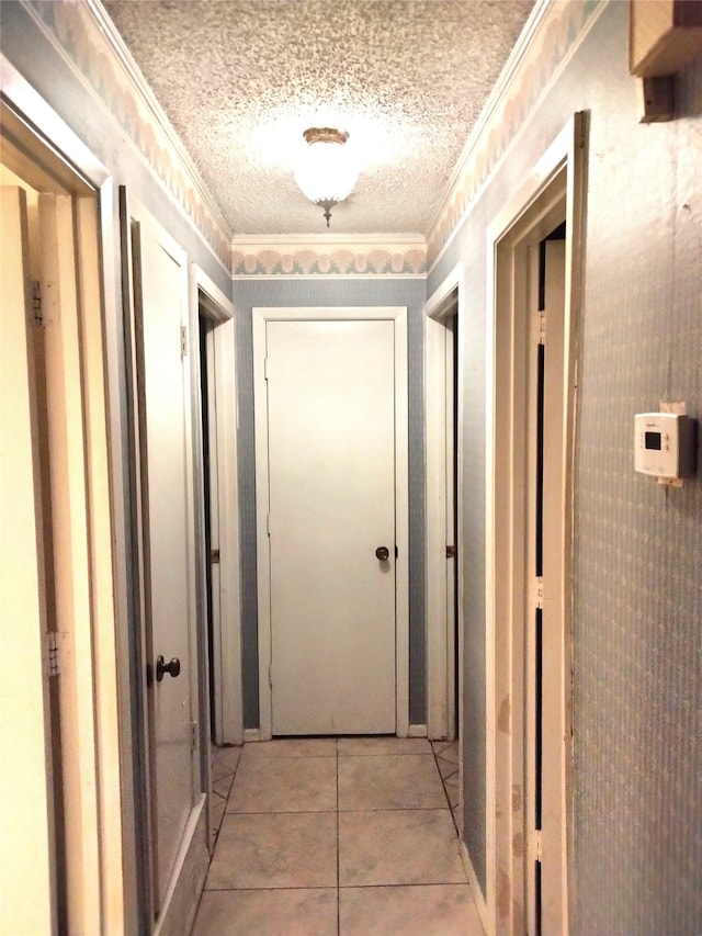 hallway with light tile patterned floors, a textured ceiling, and ornamental molding