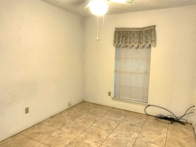 tiled spare room with ceiling fan