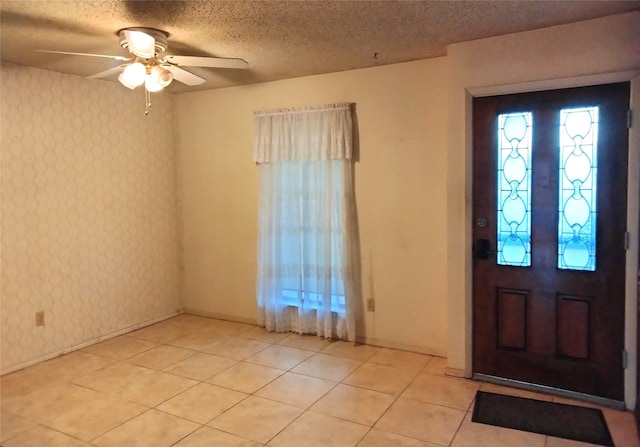 tiled foyer entrance featuring a textured ceiling and ceiling fan