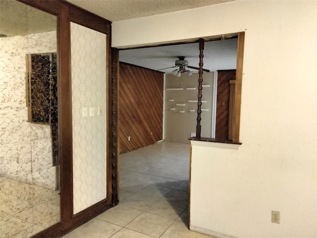 hall with wooden walls, tile patterned flooring, and a textured ceiling