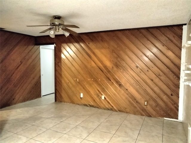 spare room featuring ceiling fan and wooden walls