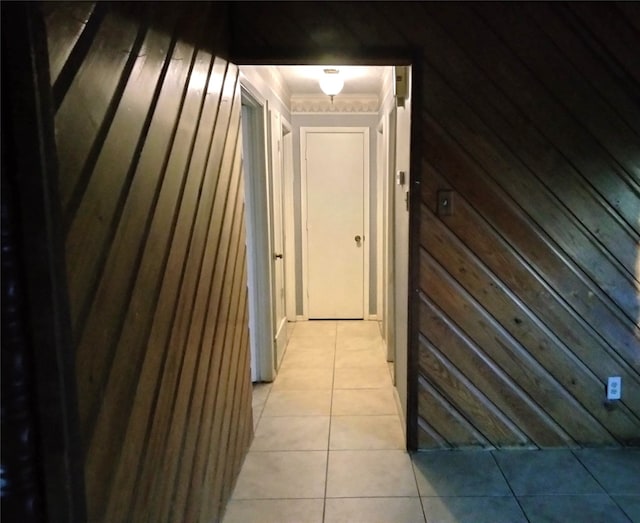 hall featuring light tile patterned floors and wood walls