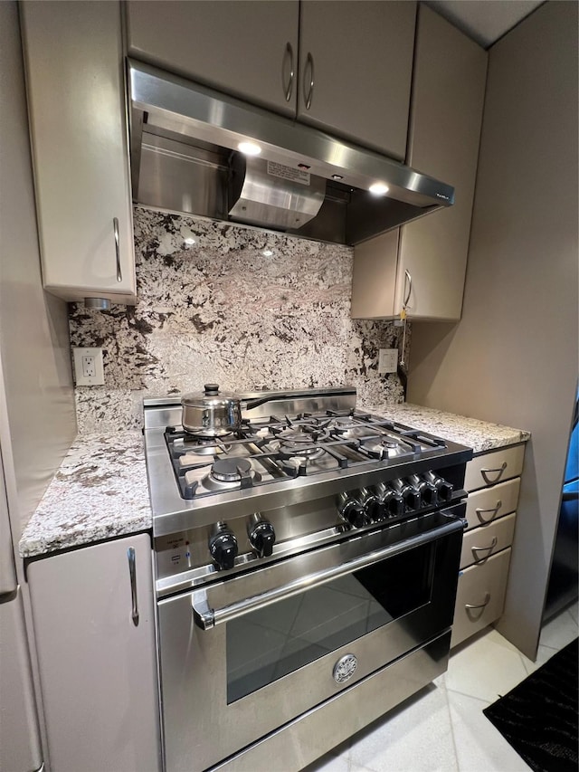 kitchen with stainless steel range, light tile patterned floors, tasteful backsplash, and light stone counters