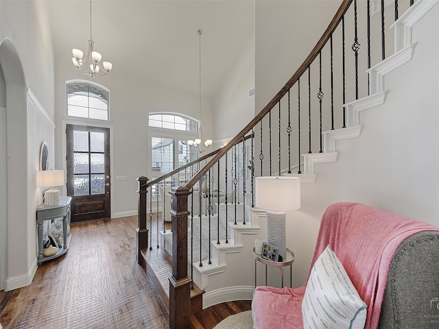 entryway with dark hardwood / wood-style flooring, high vaulted ceiling, and a notable chandelier