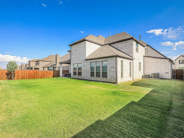 rear view of house with a yard and central AC