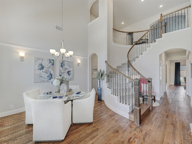 dining space featuring a towering ceiling, an inviting chandelier, and dark wood-type flooring