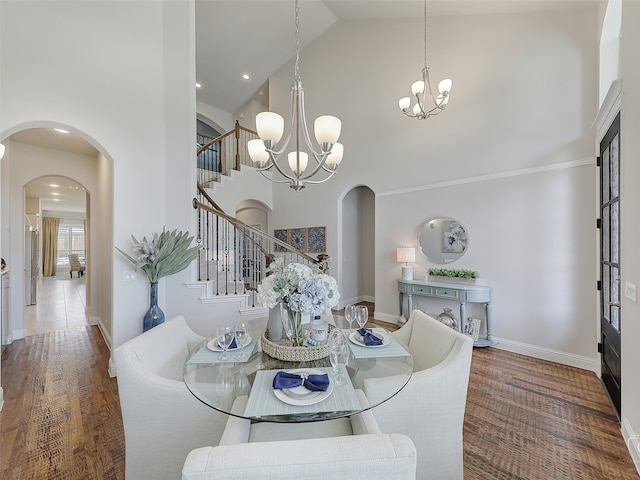 dining room with dark hardwood / wood-style flooring, high vaulted ceiling, and an inviting chandelier