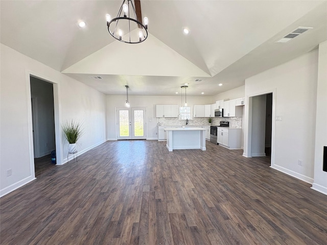 unfurnished living room with dark wood-style floors, visible vents, baseboards, and an inviting chandelier