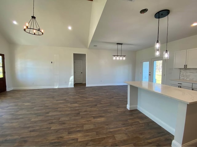 kitchen featuring backsplash, dark wood-type flooring, hanging light fixtures, light stone counters, and white cabinetry