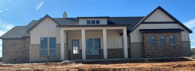 view of front of house featuring brick siding, board and batten siding, and a chimney