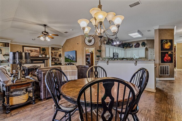 dining area with hardwood / wood-style floors, lofted ceiling, ceiling fan with notable chandelier, ornamental molding, and a textured ceiling