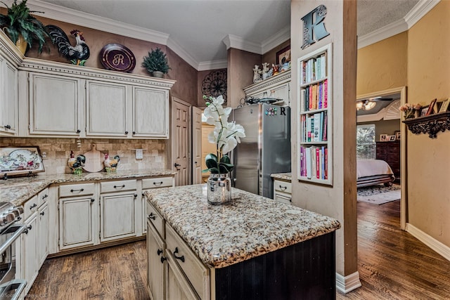 kitchen with appliances with stainless steel finishes, dark hardwood / wood-style flooring, a kitchen island, and crown molding