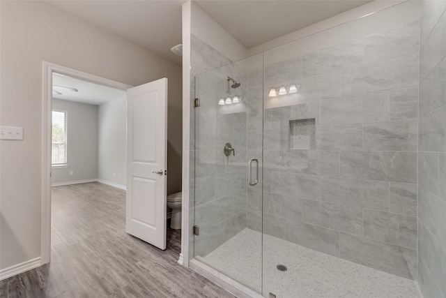 bathroom featuring wood-type flooring, toilet, and a shower with door