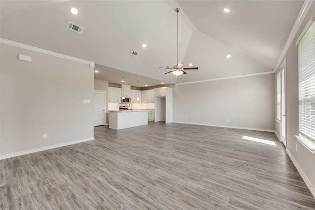 unfurnished living room featuring ceiling fan, wood-type flooring, ornamental molding, and high vaulted ceiling