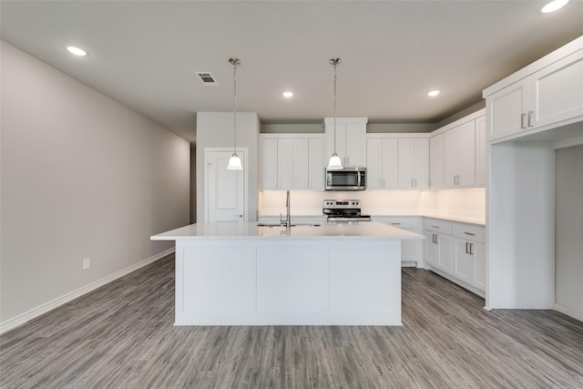 kitchen with sink, stainless steel appliances, an island with sink, pendant lighting, and white cabinets