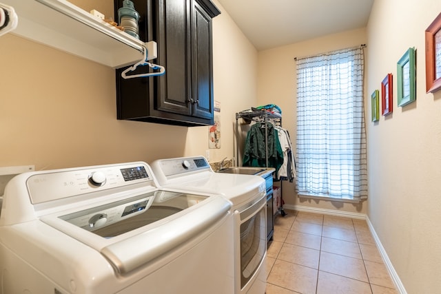 laundry room with cabinets, washing machine and dryer, and light tile patterned flooring