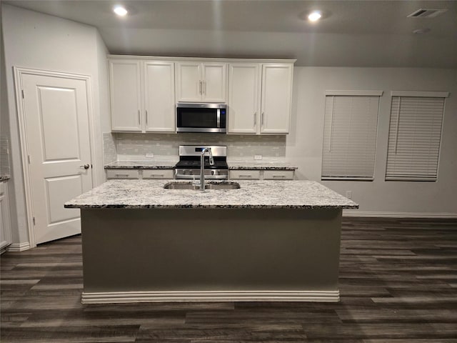 kitchen with stainless steel appliances, white cabinets, and a center island with sink