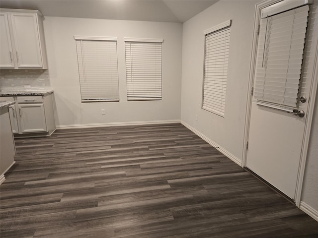 unfurnished dining area featuring dark wood-type flooring and vaulted ceiling