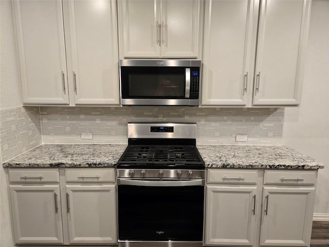 kitchen featuring white cabinetry, backsplash, stainless steel appliances, and light stone countertops