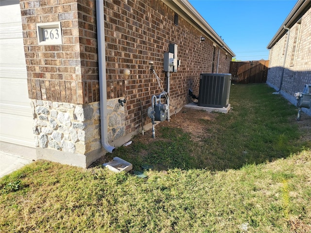 view of side of home featuring central AC unit and a lawn