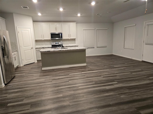 kitchen featuring light stone countertops, an island with sink, appliances with stainless steel finishes, and white cabinets