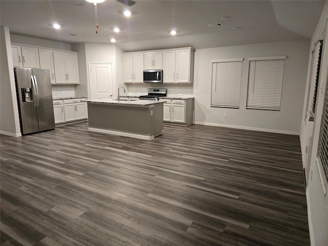 kitchen with stainless steel appliances, an island with sink, sink, and light stone counters