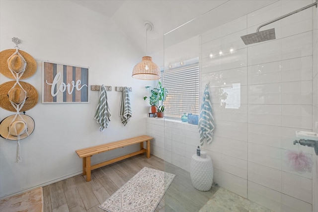 bathroom with tiled shower, wood-type flooring, and vaulted ceiling