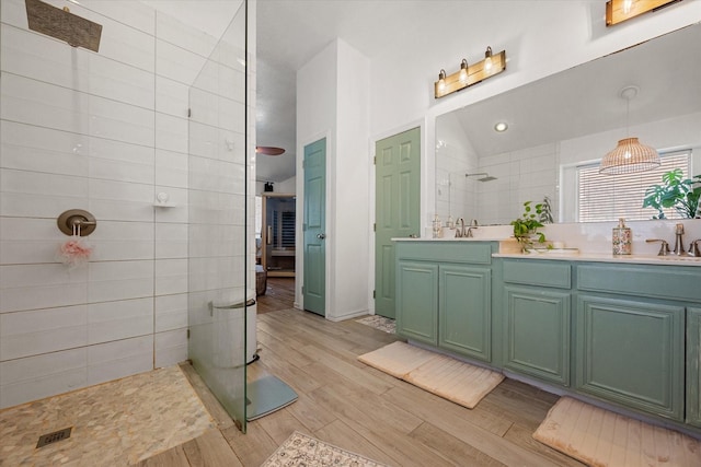 bathroom with vanity, a tile shower, and wood-type flooring