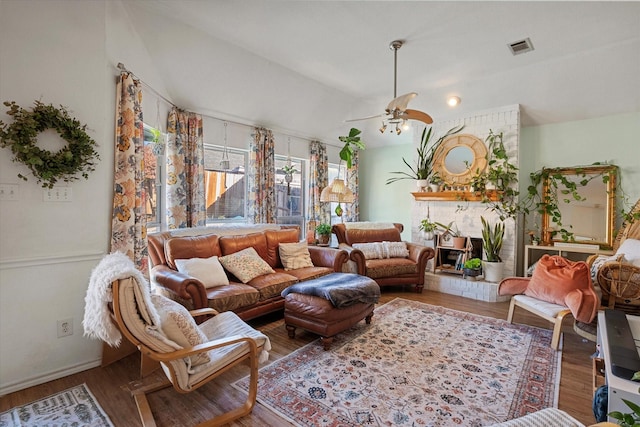 sitting room with ceiling fan, wood-type flooring, and a brick fireplace