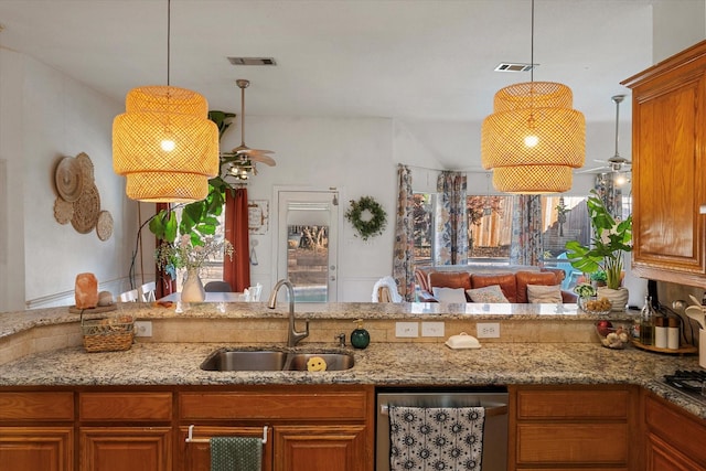 kitchen with light stone countertops, dishwasher, sink, and hanging light fixtures