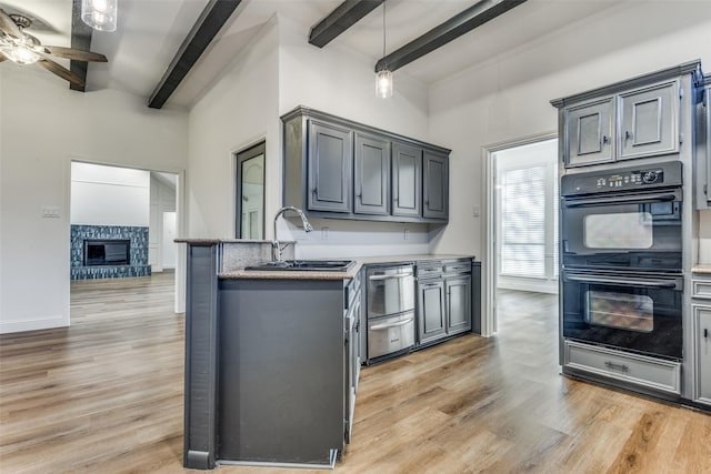 kitchen featuring gray cabinetry, ceiling fan, beamed ceiling, double oven, and light wood-type flooring