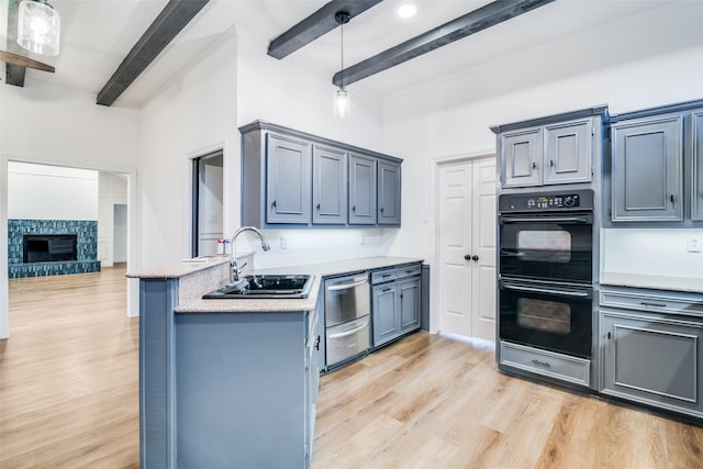 kitchen with black double oven, sink, pendant lighting, beam ceiling, and a fireplace