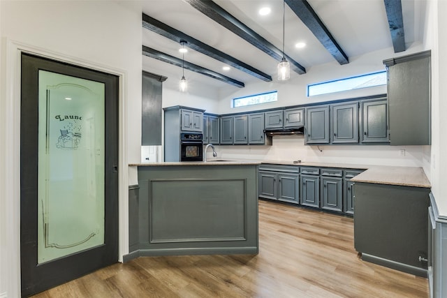 kitchen featuring beam ceiling, light wood-type flooring, black oven, and pendant lighting