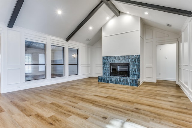 unfurnished living room with a fireplace, lofted ceiling with beams, and light hardwood / wood-style flooring