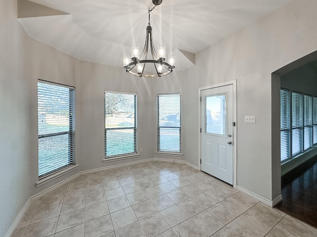 foyer entrance with an inviting chandelier, plenty of natural light, and light tile patterned flooring