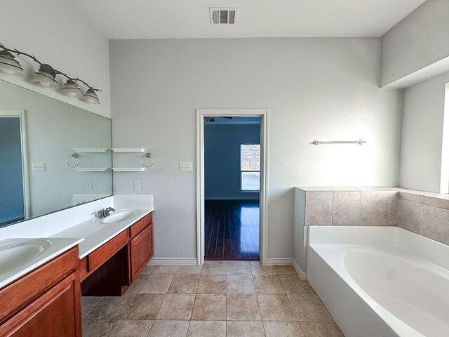 bathroom with tile patterned flooring, vanity, and tiled bath