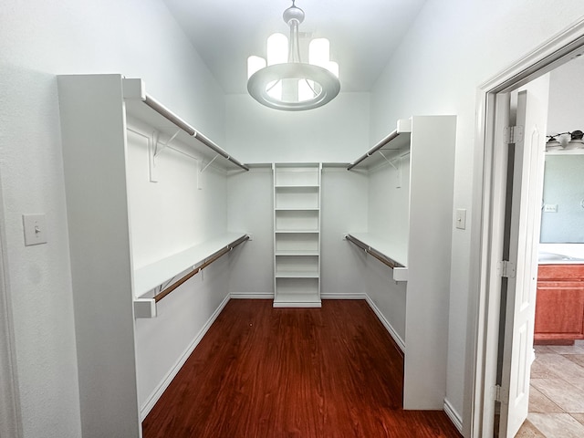 walk in closet with hardwood / wood-style floors and an inviting chandelier