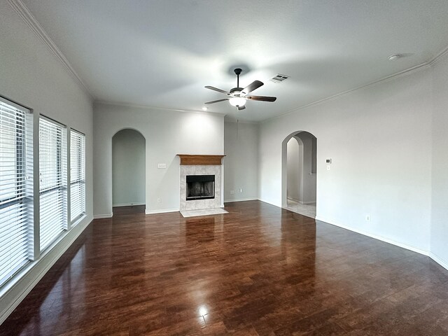 unfurnished living room featuring ceiling fan, crown molding, a wealth of natural light, and a tiled fireplace