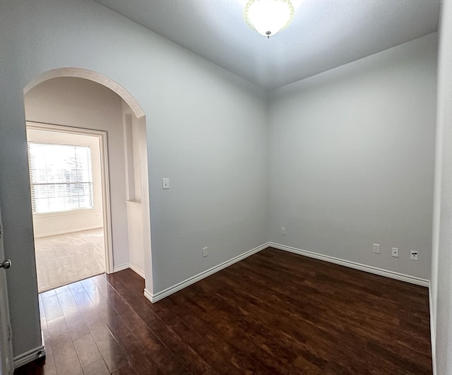 unfurnished room with dark wood-type flooring