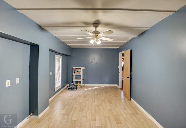 empty room with beam ceiling, ceiling fan, and light wood-type flooring