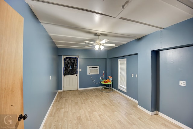 empty room with a wall unit AC, ceiling fan, and light wood-type flooring