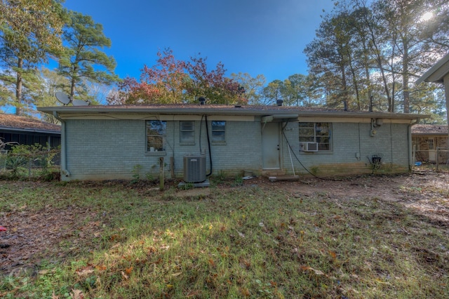 back of house with cooling unit and a lawn