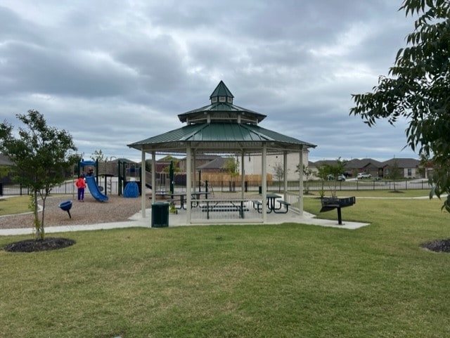 view of community featuring a playground, a gazebo, and a lawn