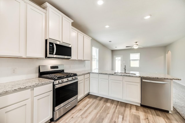 kitchen with sink, light hardwood / wood-style flooring, appliances with stainless steel finishes, backsplash, and white cabinets